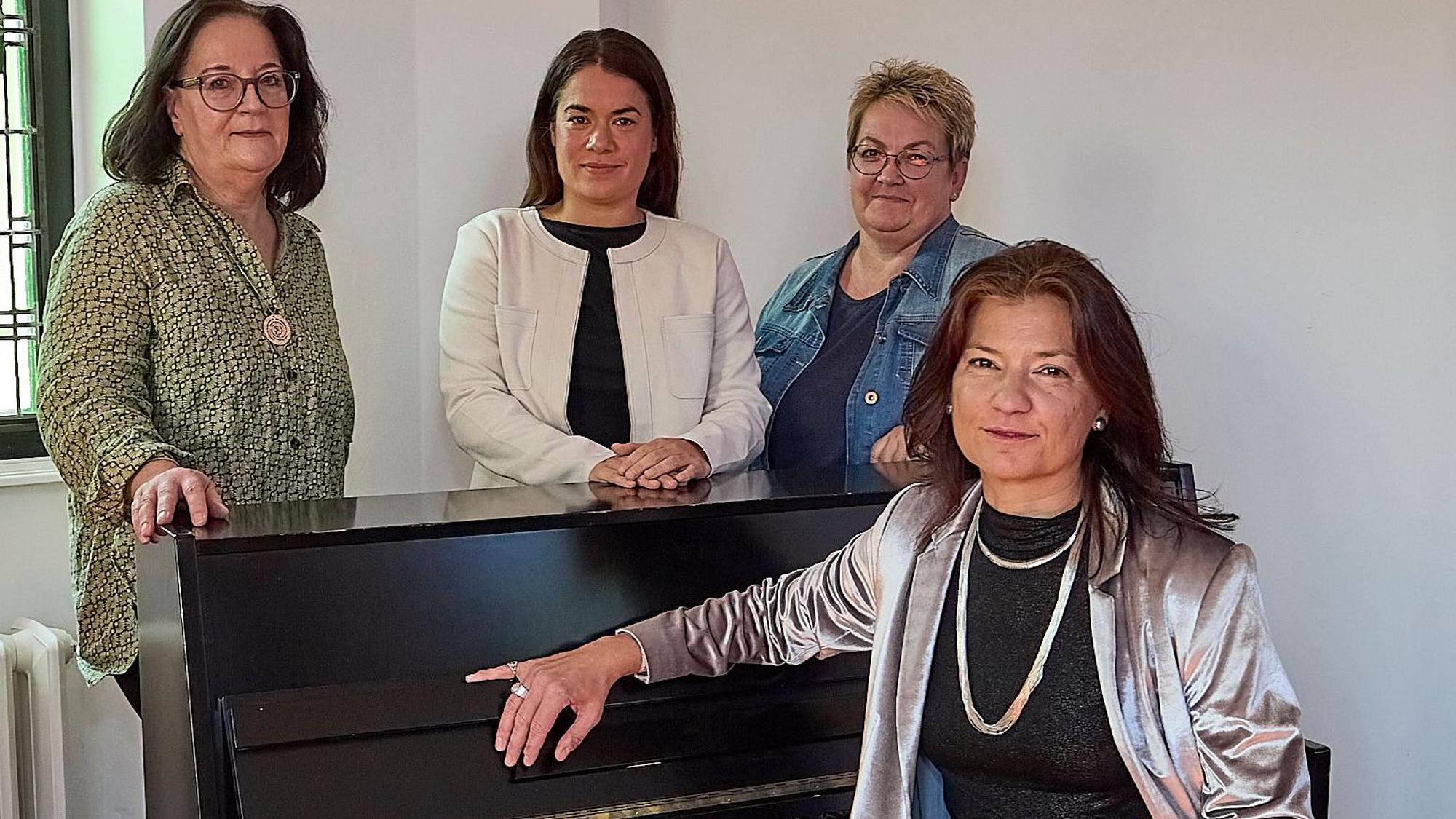 Eine Frau im silbernen Glitzer-Outfit sitzt am Klavier, drei andere Frauen haben sich dahinter postiert, alle schauen in die Kamera.