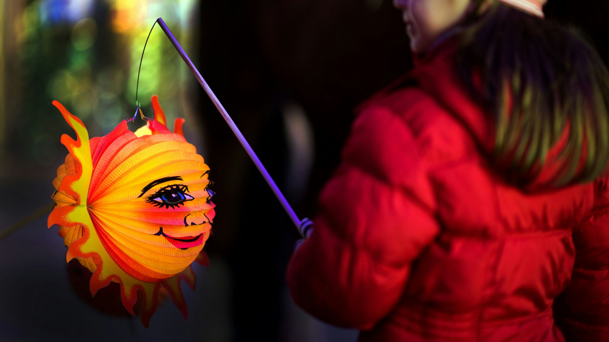 Ein Mädchen hält während eine Laterne in der Hand.