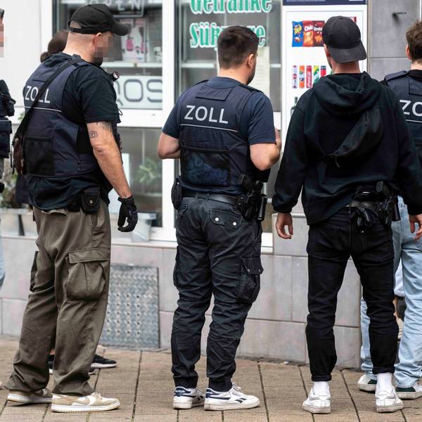 Das Bild zeigt den Moment der Durchsuchung, bei dem die Beamten in den Kiosk gehen.
