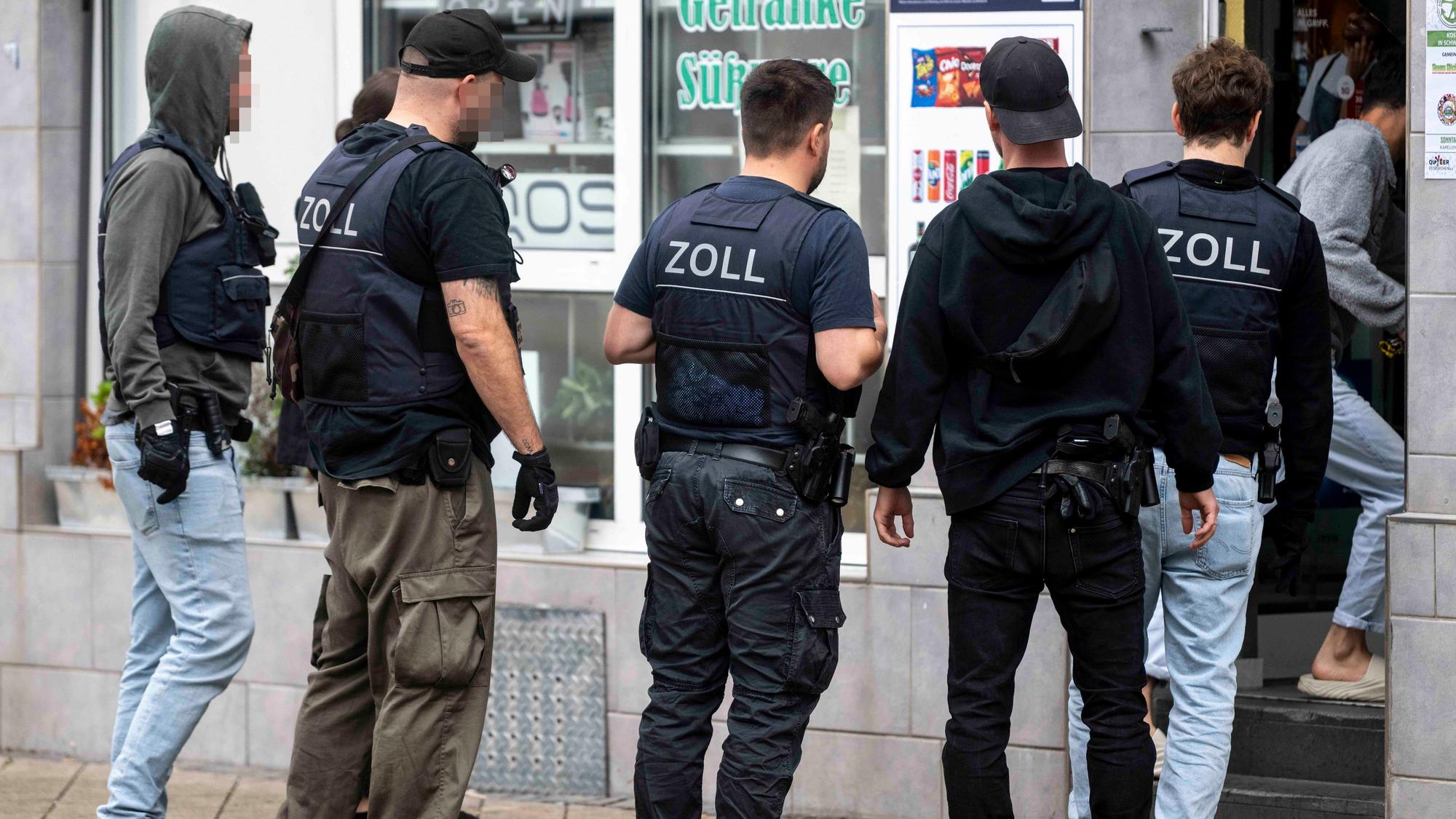 Das Bild zeigt den Moment der Durchsuchung, bei dem die Beamten in den Kiosk gehen.