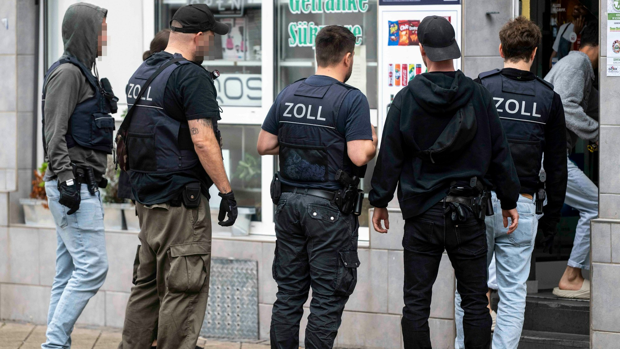 Das Bild zeigt den Moment der Durchsuchung, bei dem die Beamten in den Kiosk gehen.