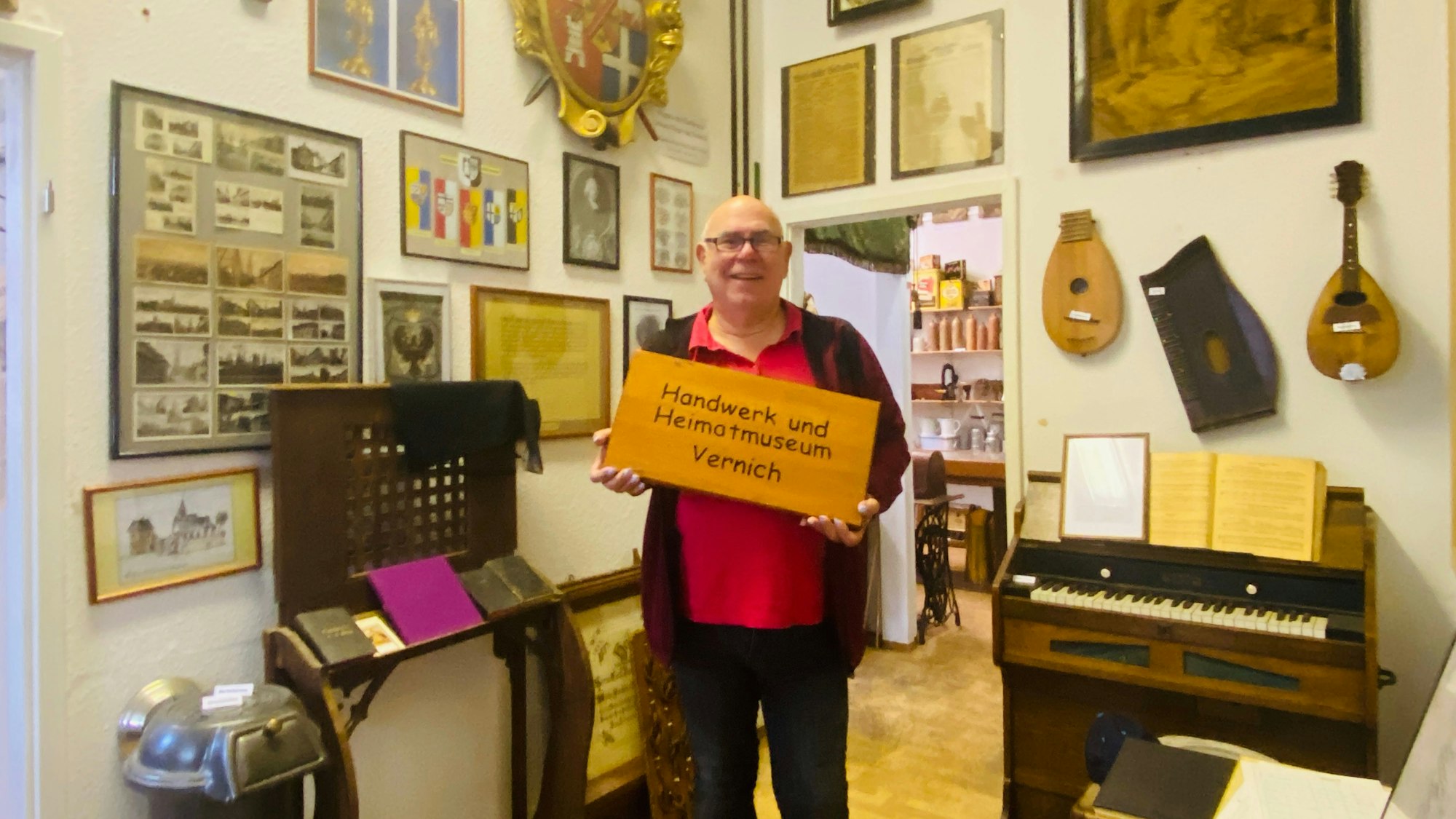 Karl-Heinz Nauroth steht in einem Museumsraum voller Exponate, darunter Instrumente und Bilder.