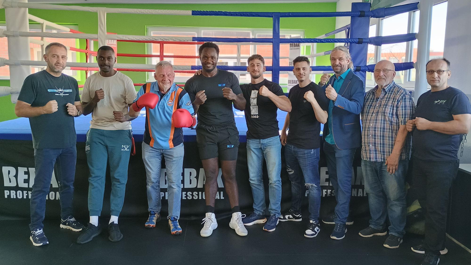 Die Beteiligten stehen in einer Reihe zu recken die Fäuste, hinter ihnen der Ring.