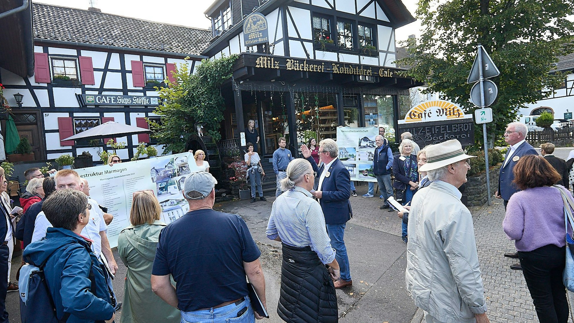 Vor dem Fachwerkbau der Bäckerei Milz stehen zahlreiche Menschen.