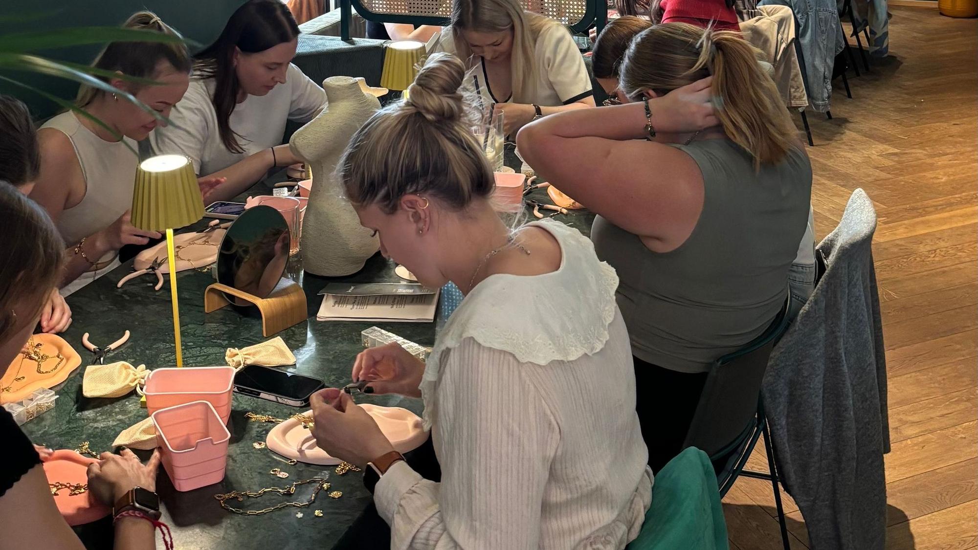 Die Teilnehmenden bei den Ketten-Workshops befestigen Anhänger mithilfe kleiner Zangen an den Ketten.