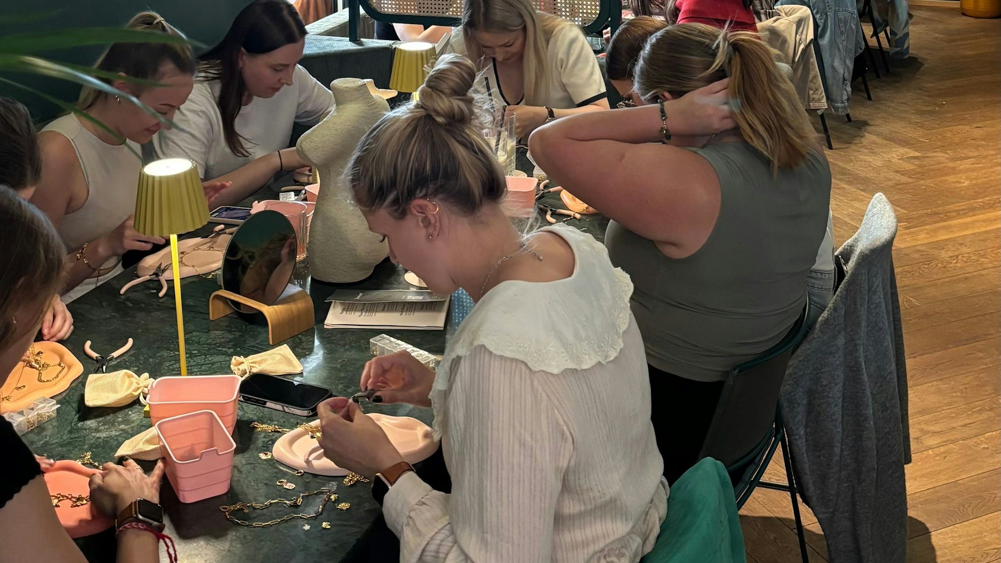Die Teilnehmenden bei den Ketten-Workshops befestigen Anhänger mithilfe kleiner Zangen an den Ketten.