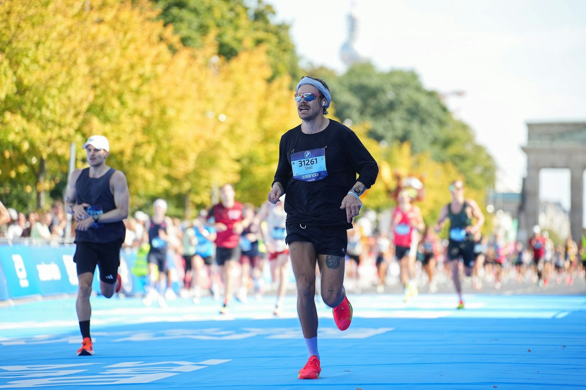 Der britische Sänger und Schauspieler Harry Styles (r) startete unter falschem Namen beim Berlin-Marathon.