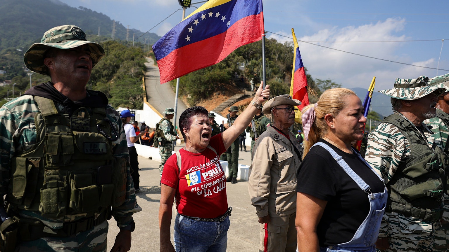 Eine Frau, Mitte, hält eine Nationalflagge während einer Militärübung hoch.
