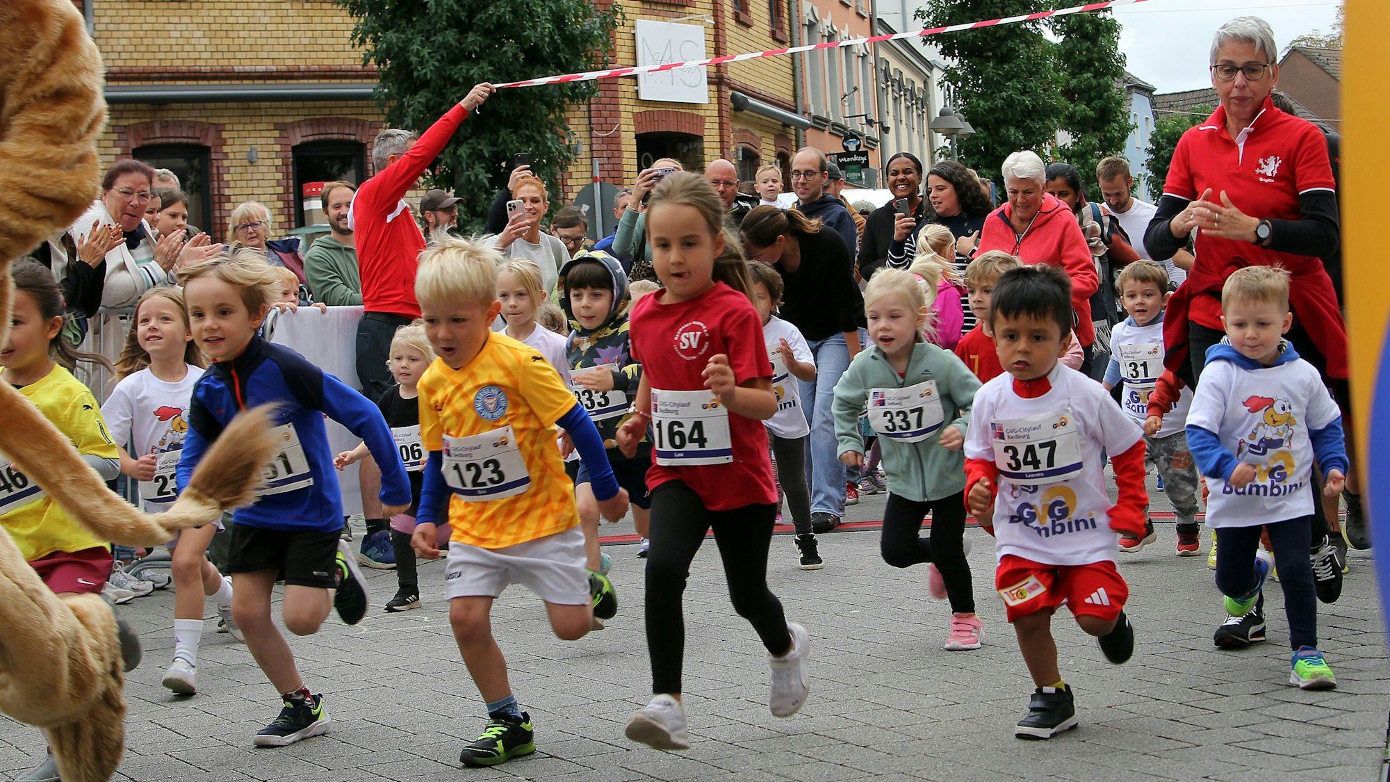 Auf dem Bild sind kleine Kinder in Sportsachen zu sehen, die zu einem Lauf starten.