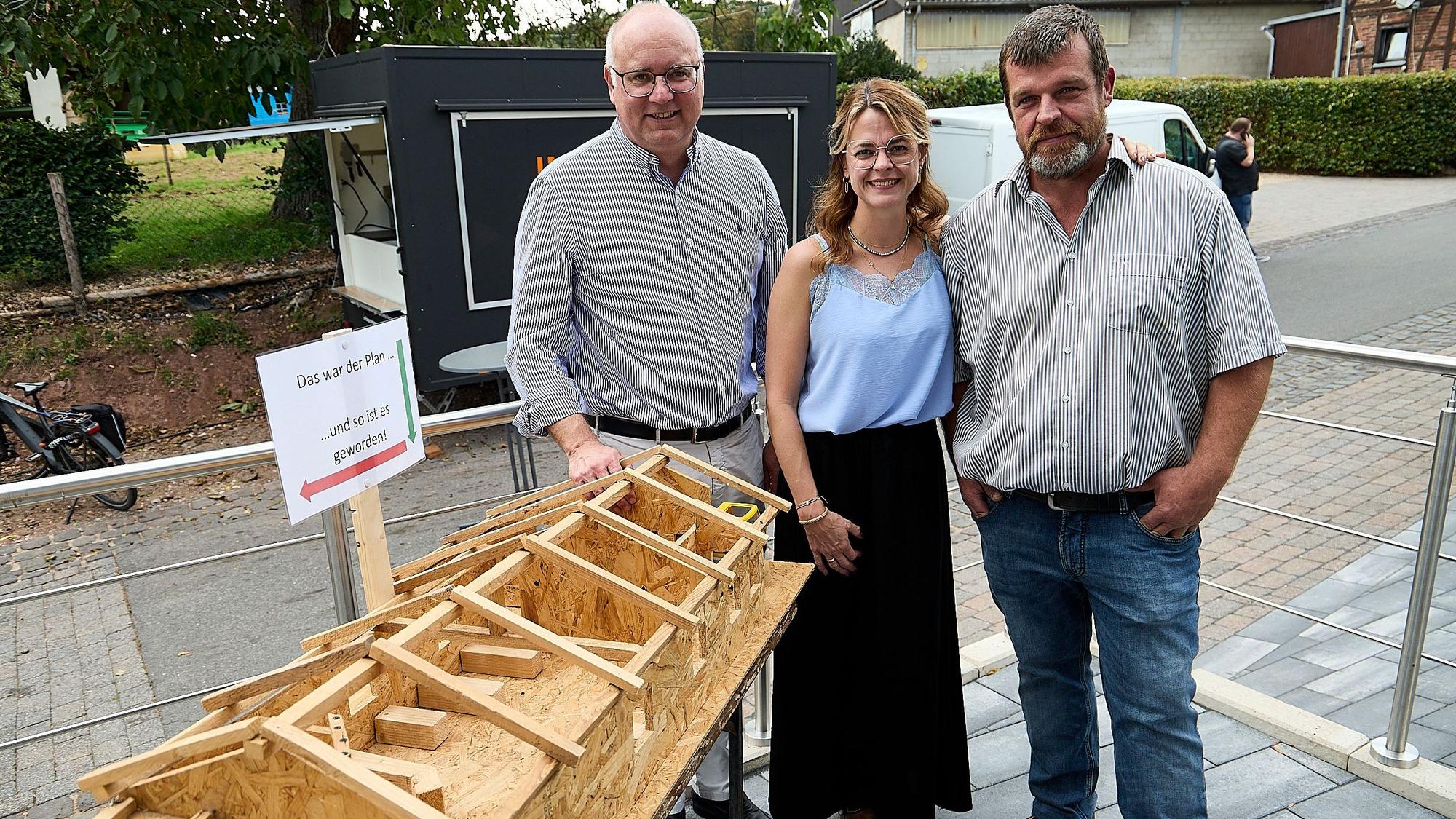Der Bürgermeister und die beiden Vorstandsmitglieder betrachten das ausgestellte Holzmodell der Halle.