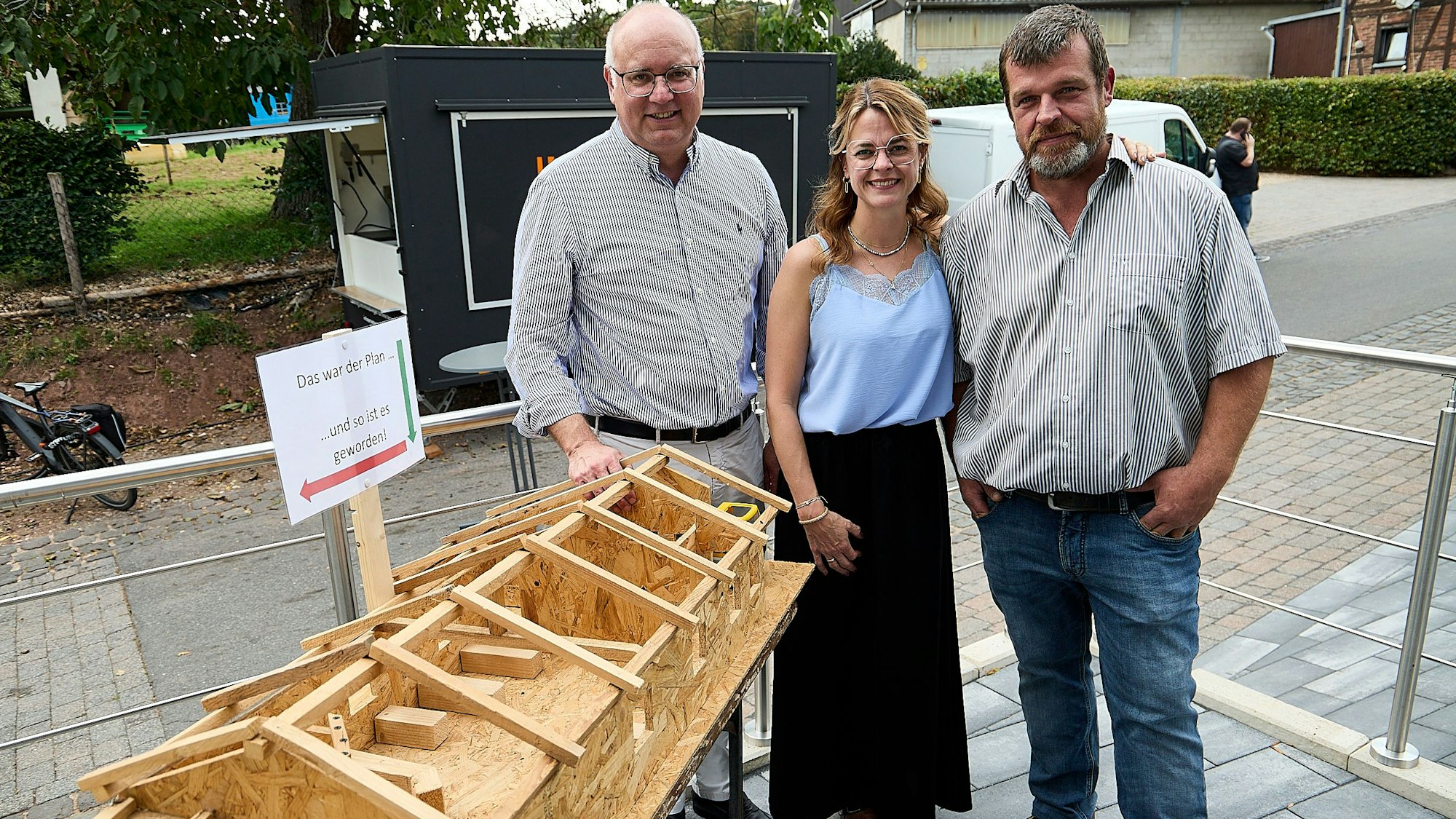 Der Bürgermeister und die beiden Vorstandsmitglieder betrachten das ausgestellte Holzmodell der Halle.
