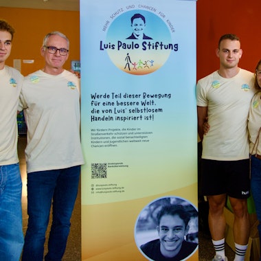 Zu sehen sind vier Menschen neben einem Aufsteller.