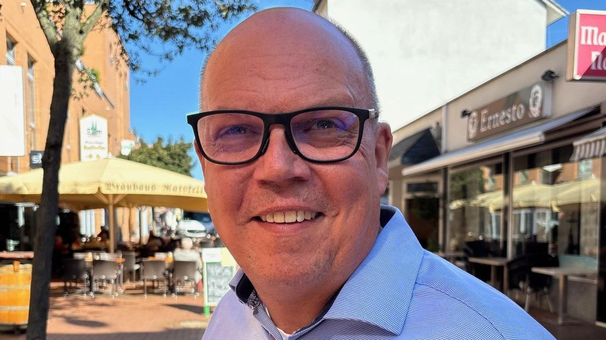 Auf dem Bild ist ein Portrait von Uwe Tietz zu sehen, er trägt ein hellblaues Hemd.