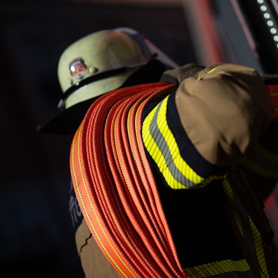 Eine Einsatzkraft der Feuerwehr nimmt einen Schlauch aus einem Einsatzfahrzeug. (Symbolbild)