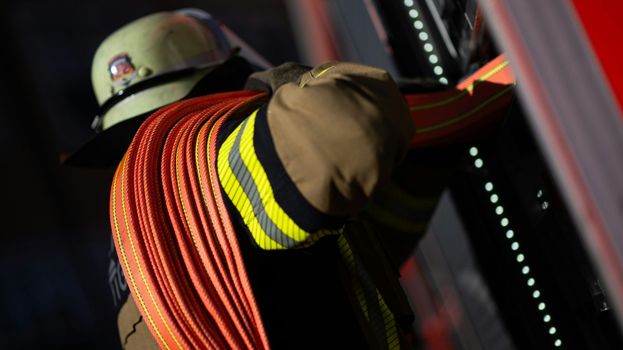 Eine Einsatzkraft der Feuerwehr nimmt einen Schlauch aus einem Einsatzfahrzeug. (Symbolbild)