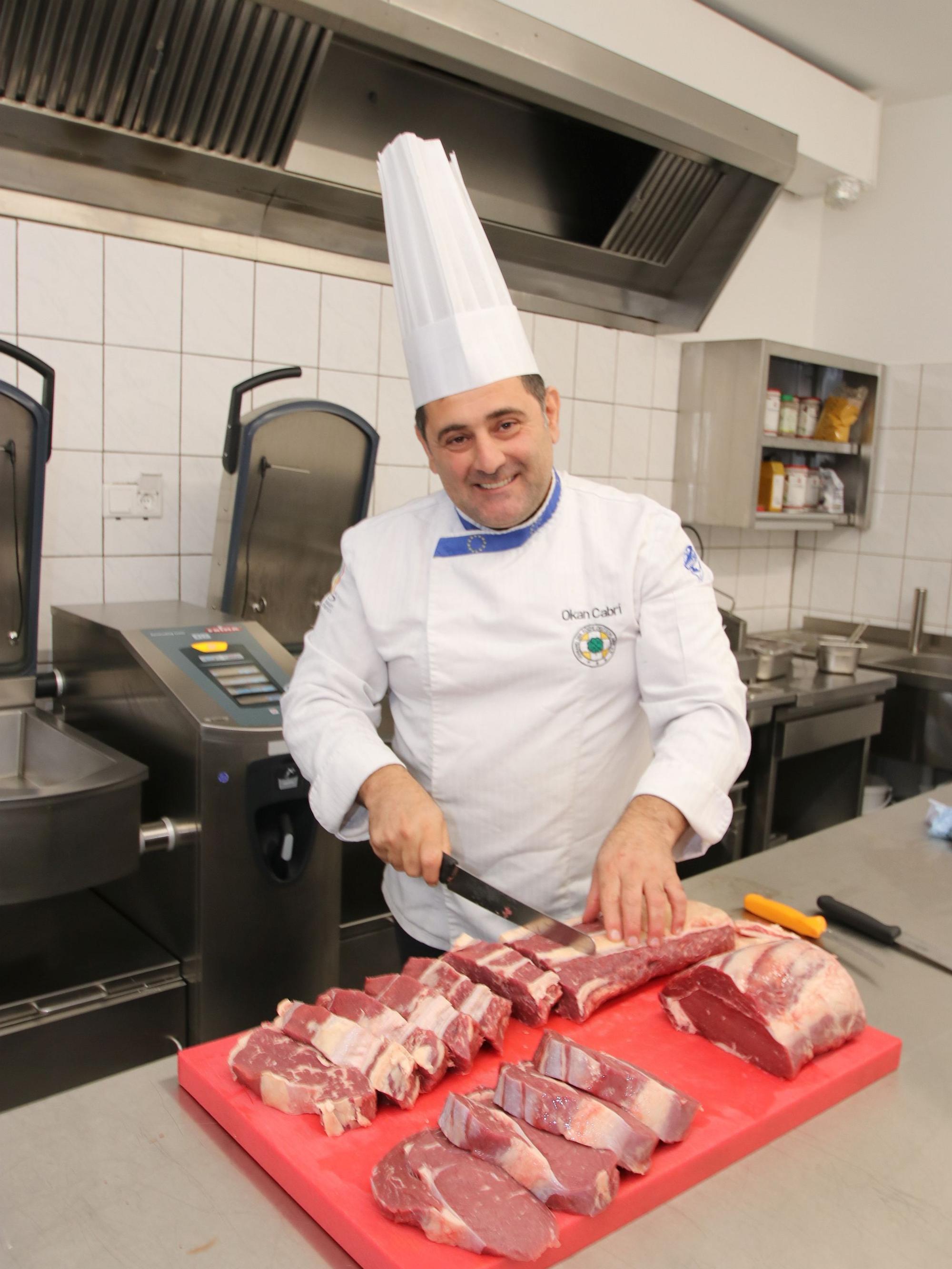Das Bild zeigt den Chef beim Schneiden von Steaks.