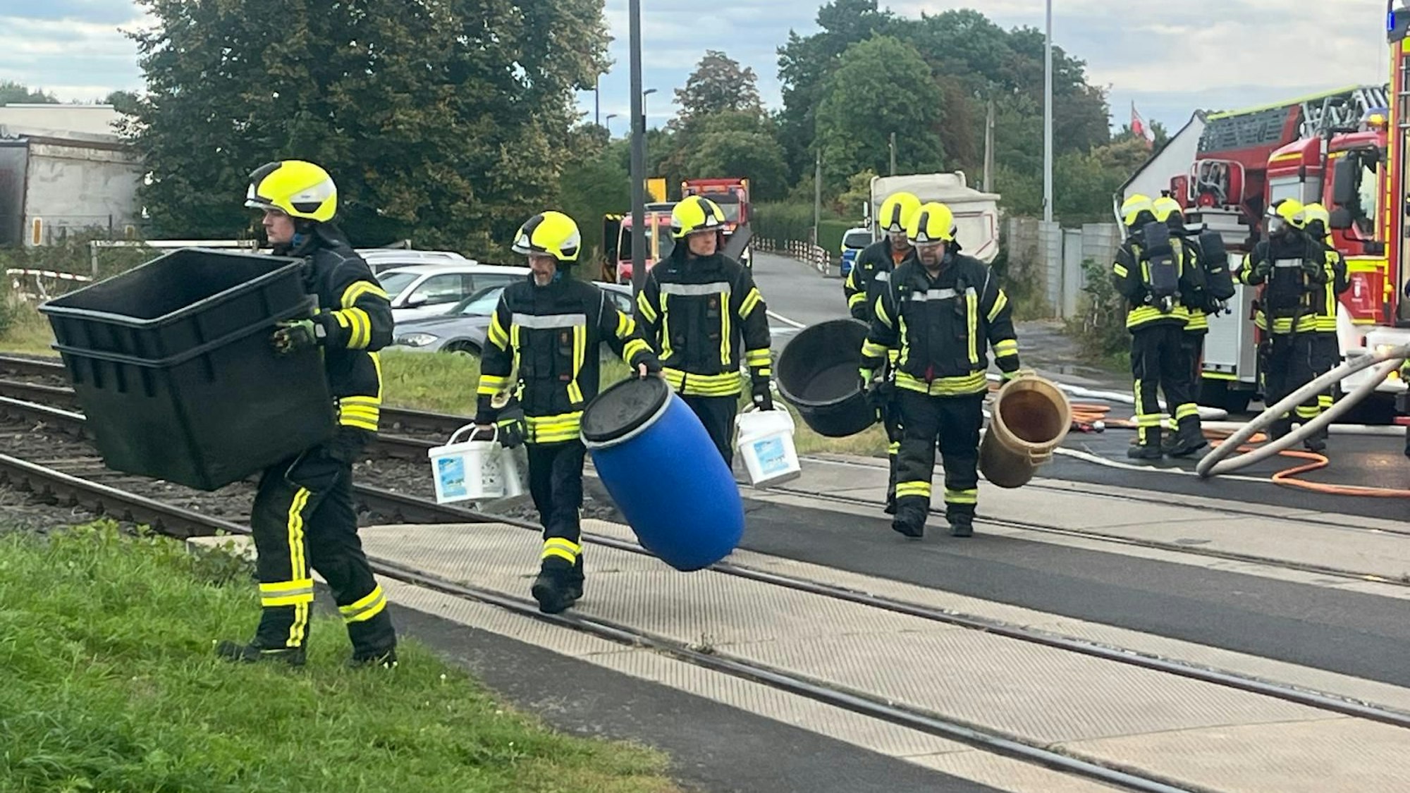Einsatzkräfte tragen Plastikwannen über die Gleise, um das Wasserstoffperoxid aufzufangen.