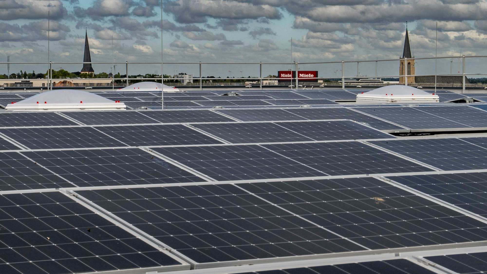 Das Bild zeigt zahlreiche PV-Module. Im Hintergrund sind die Herz-Jesu-Kirche und die Martinskirche zu sehen.