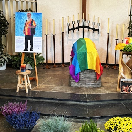 Blick auf eine bunte Urne und bunte Tücher in einer Friedhofshalle