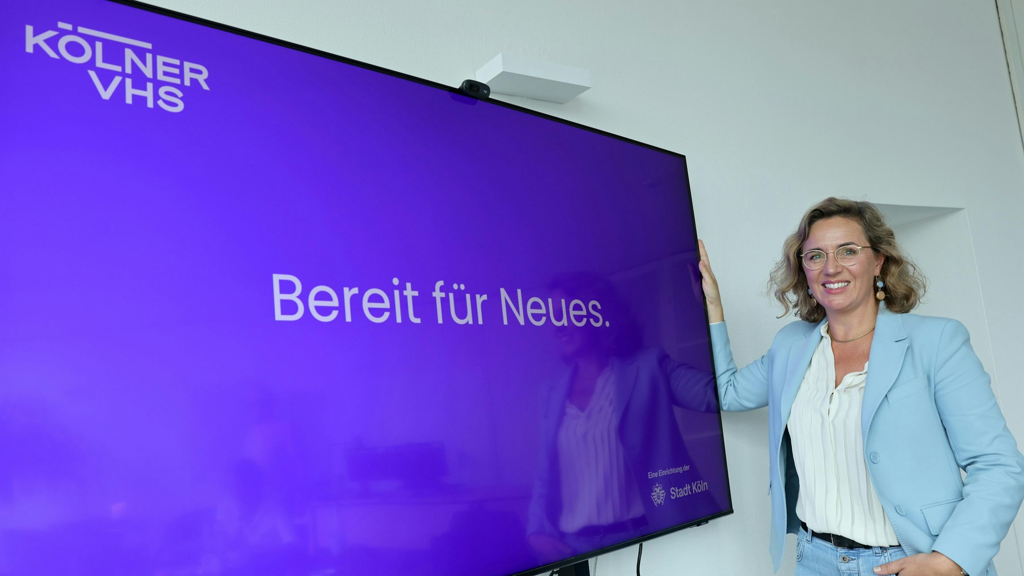 Dr. Marie Batzel vor der neuen Homepage der Kölner VHS.
