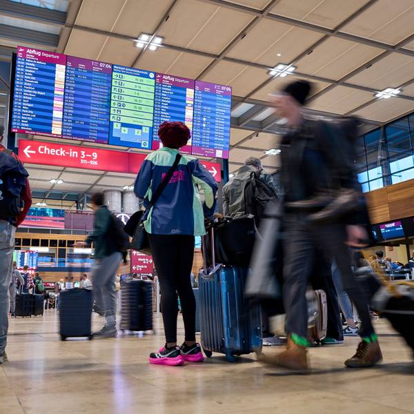 Fluggäste informieren sich nach einem Cyberangriff an den Abflugtafeln im Terminal 1 des Flughafens Berlin-Brandenburg.