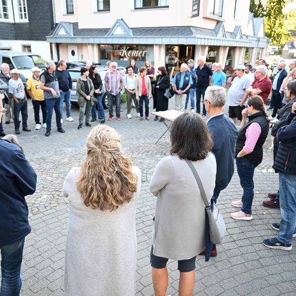Menschen stehen auf einem Platz und diskutieren miteinander.