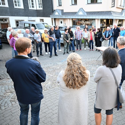 Menschen stehen auf einem Platz und diskutieren miteinander.