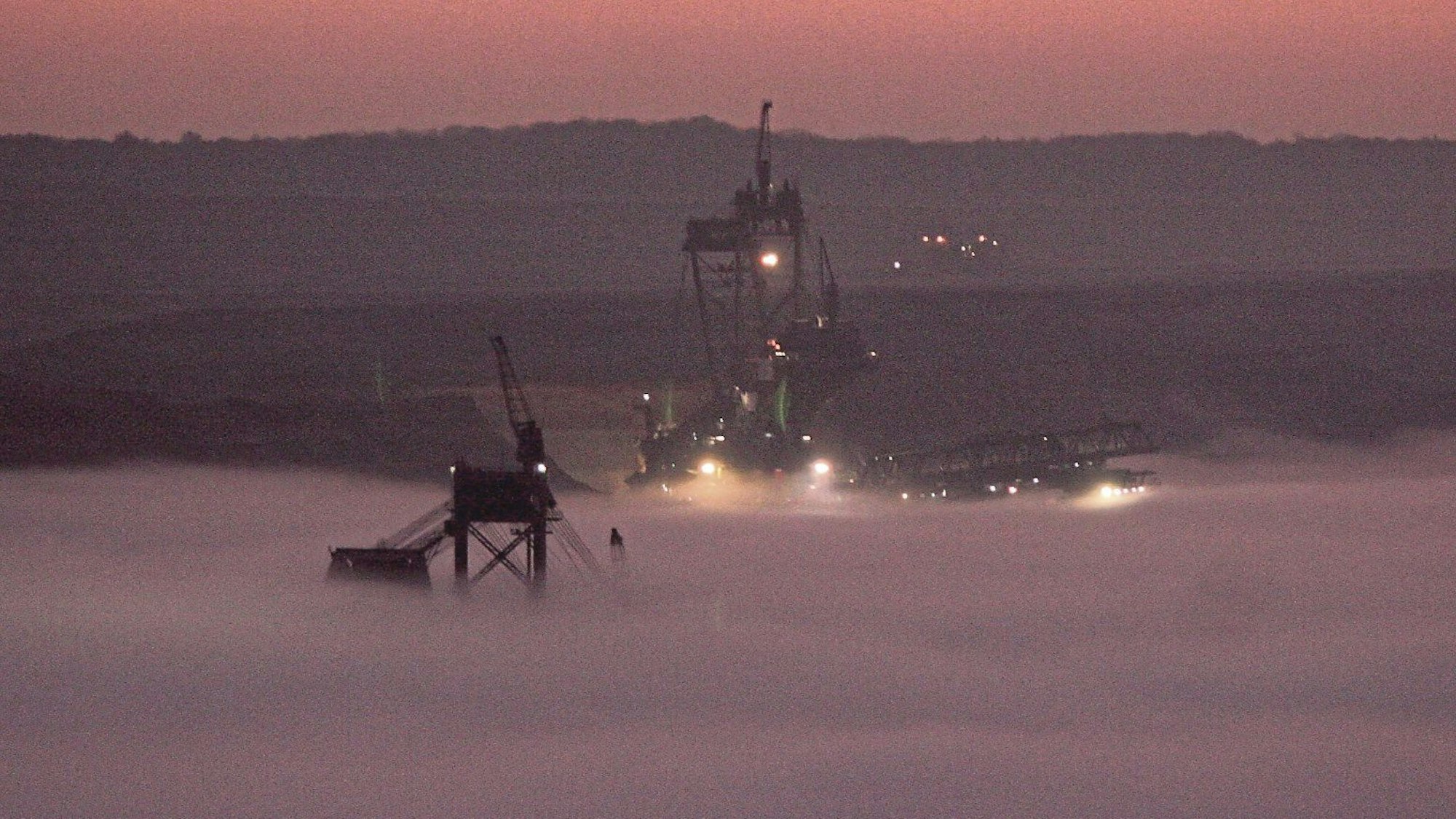 Zu sehen ist, wie Nebel Bagger im Tagebau Hambach einhüllt.
