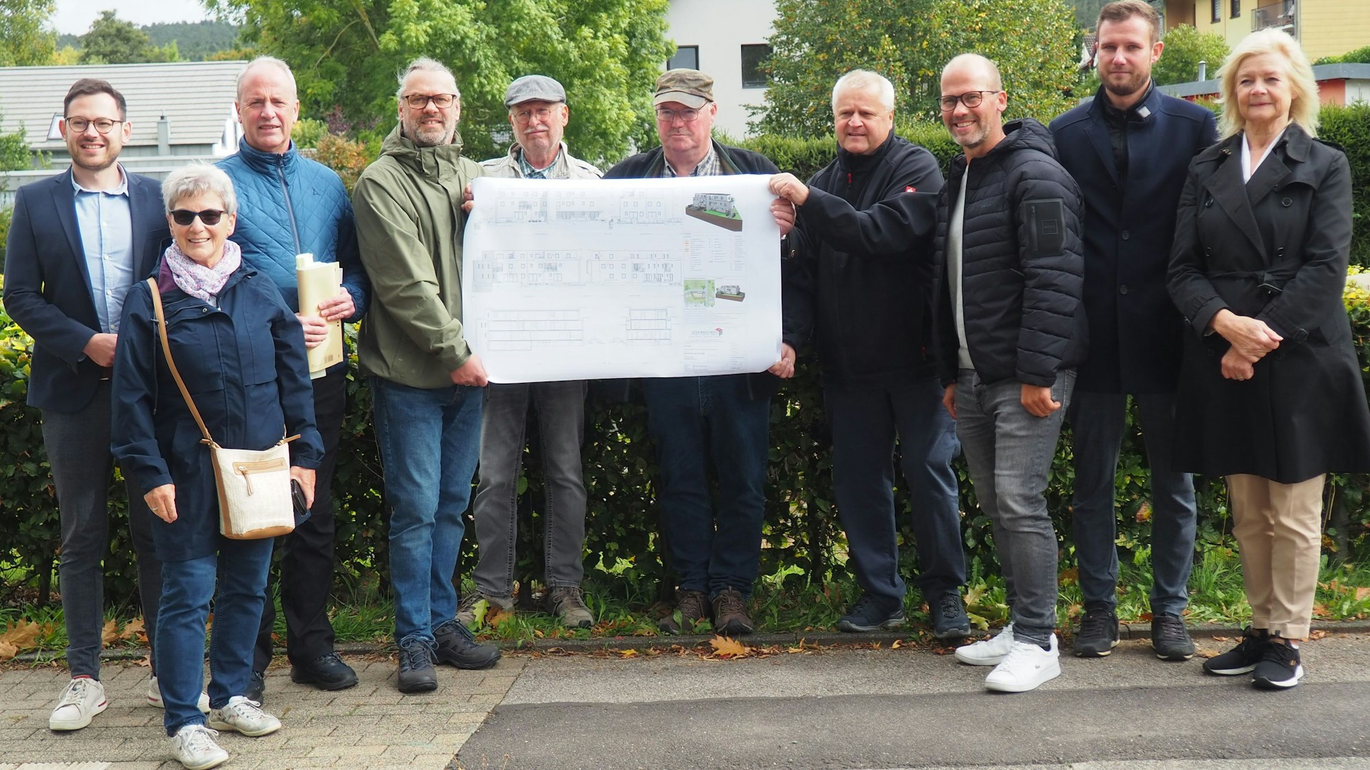 Eine Gruppe Menschen steht zusammen, einige halten einen Plan hoch.