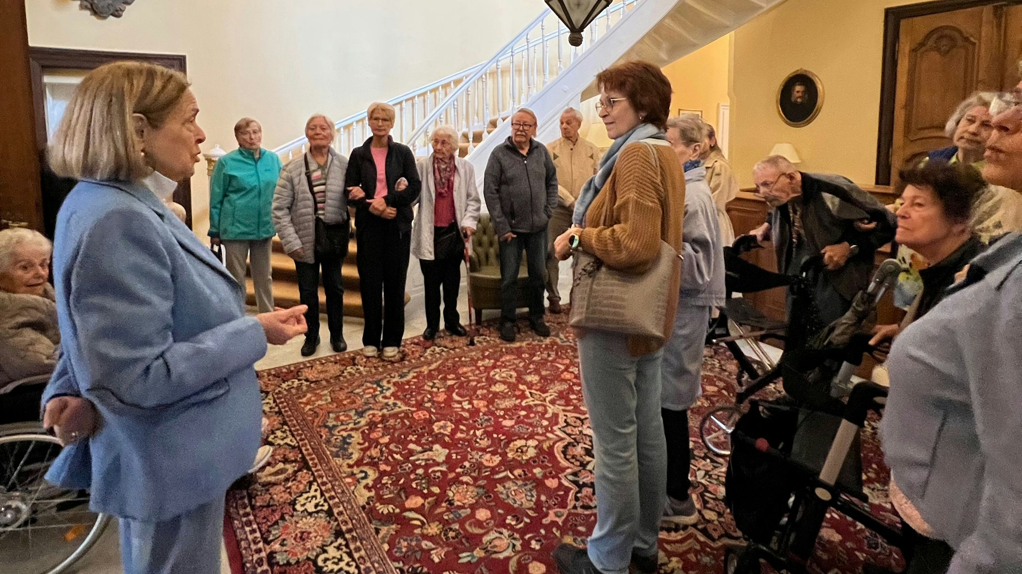 Männer und Frauen stehen im Eingangsbereich eines Schlosses.