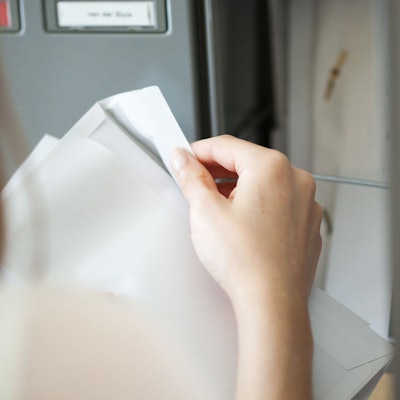 Eine Frau öffnet am Briefkasten einen Brief.