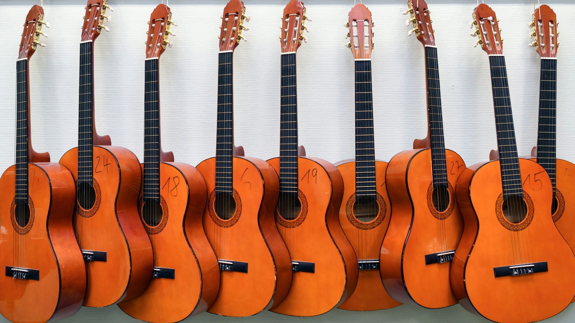 Symbolbild: Nummerierte Gitarren hängen an einer Wand.