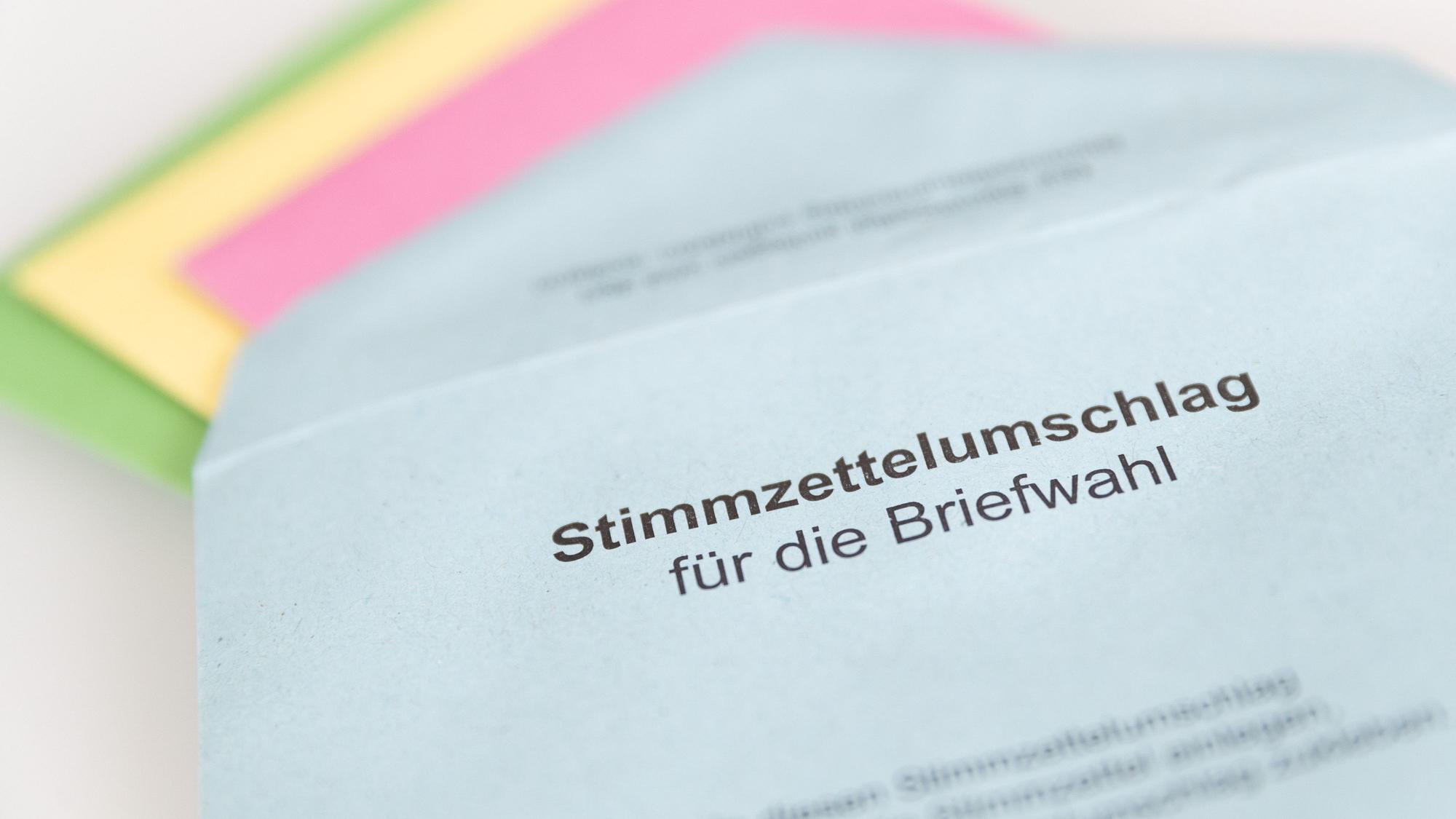 Verschiedene Stimmzettel stecken in einem Stimmzettelumschlag für die Briefwahl.