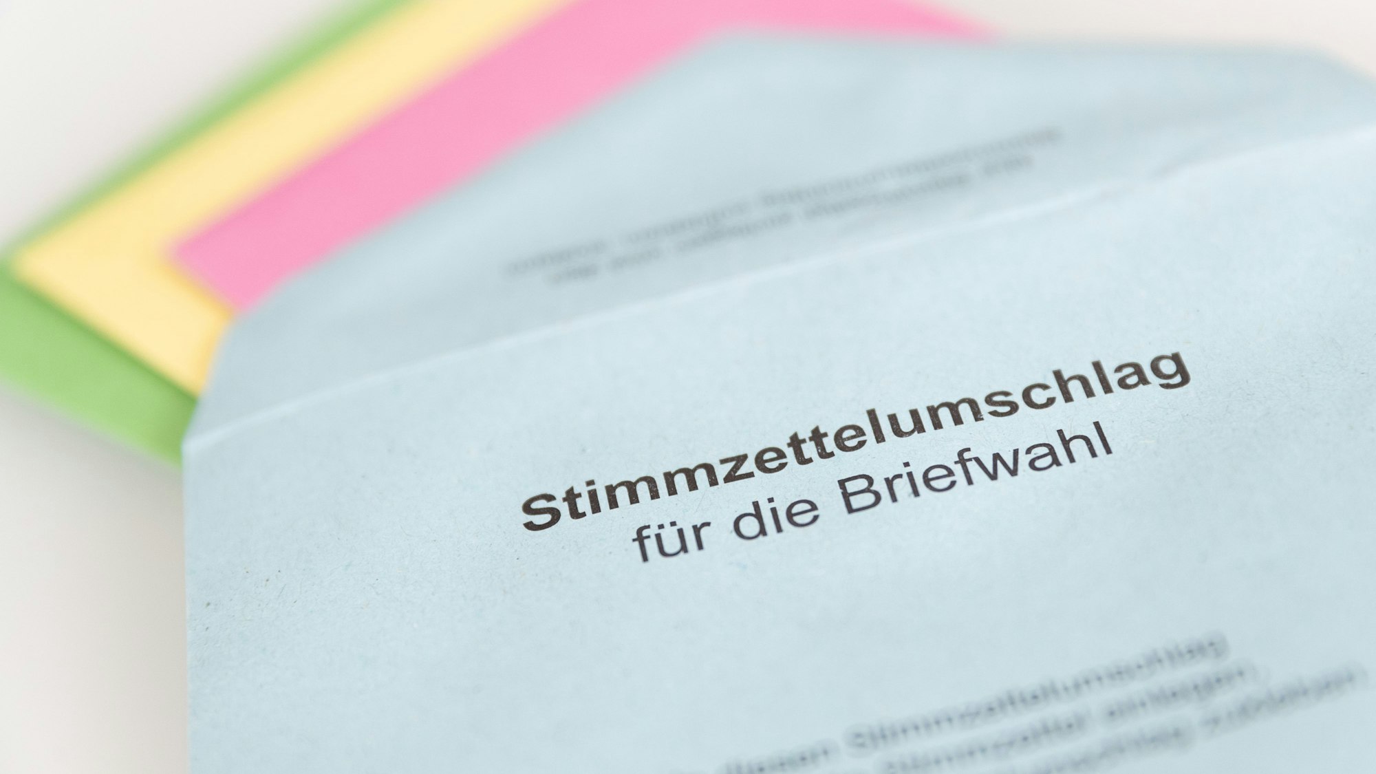 Verschiedene Stimmzettel stecken in einem Stimmzettelumschlag für die Briefwahl.