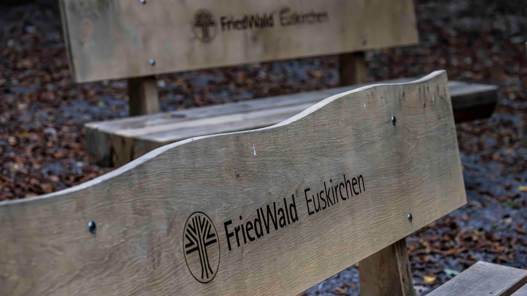 Das Bild zeigt zwei Holzbänke für Trauergäste. Sie tragen die Inschrift: Friedwald Euskirchen.