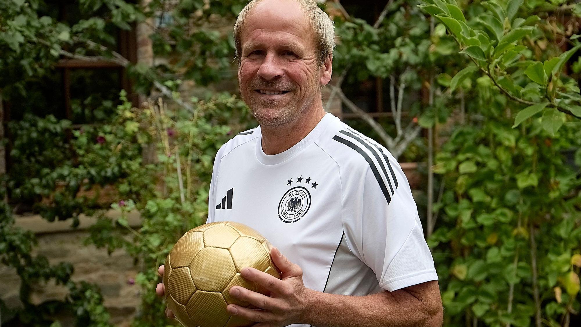 Peter Siebert trägt das Deutschland-Trikot und hält einen goldenen Fußball in den Händen.