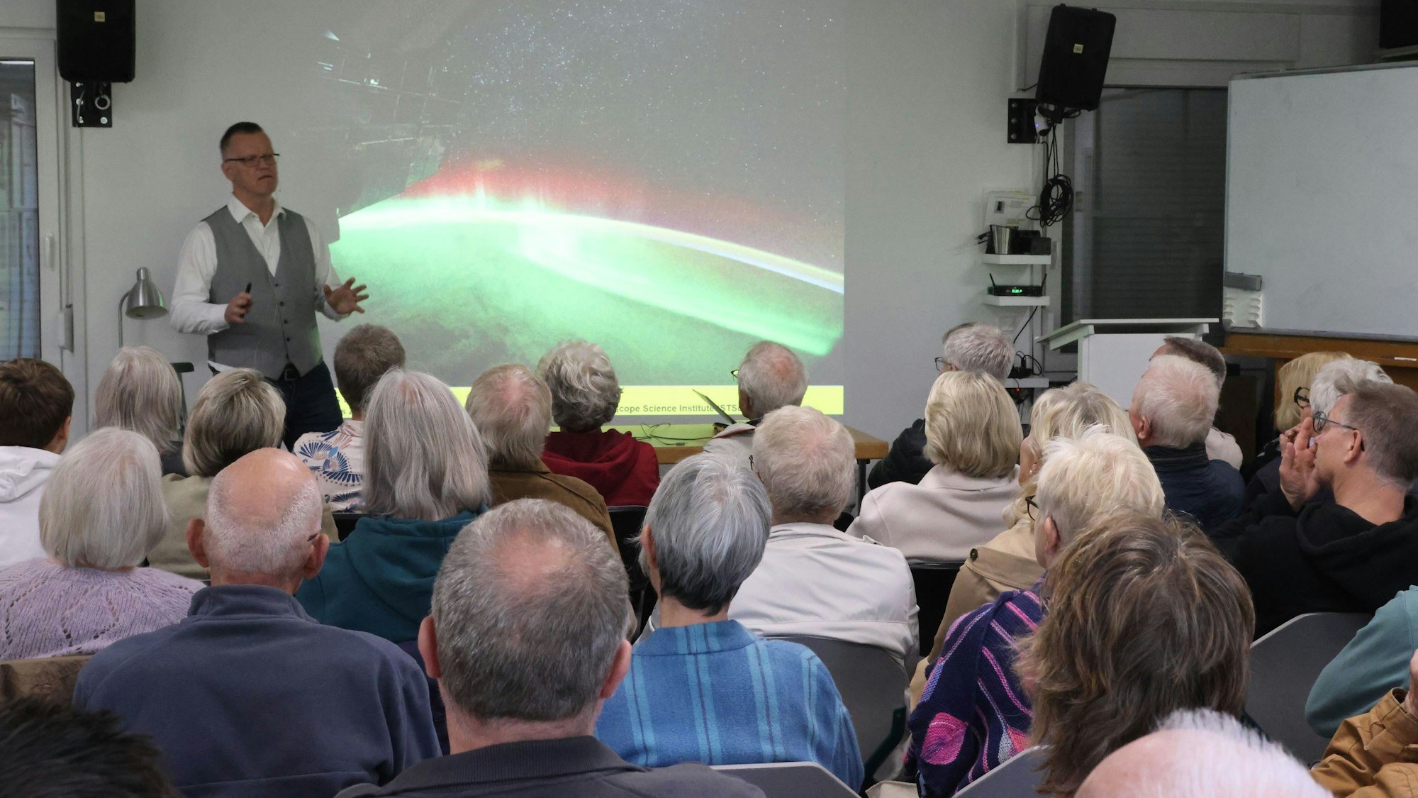 Gespannt lauschen Zuhörerinnen und Zuhörer einem Vortragenden.