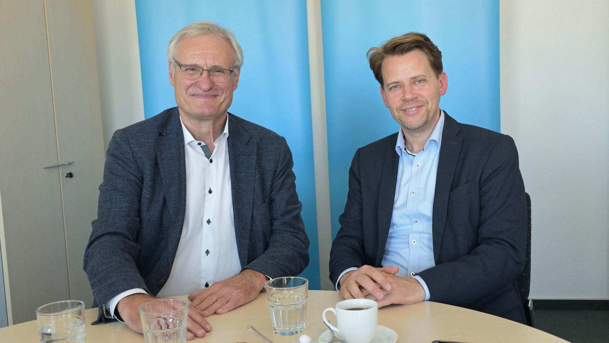 Beide Landratskandidaten lächeln in die Kamera.