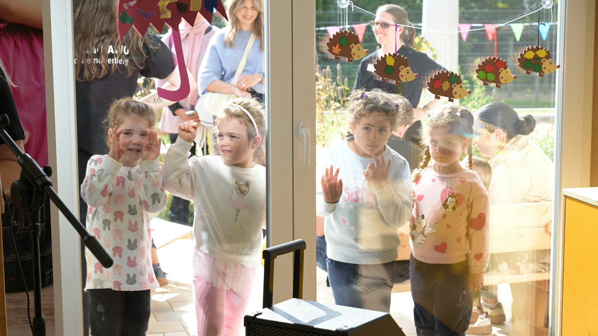 Vier Kinder blicken durch die Fensterscheibe.