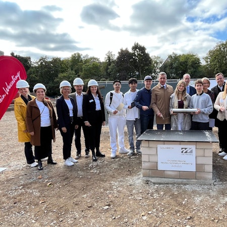 Das Foto zeigt Menschen bei einer Grundsteinlegung.