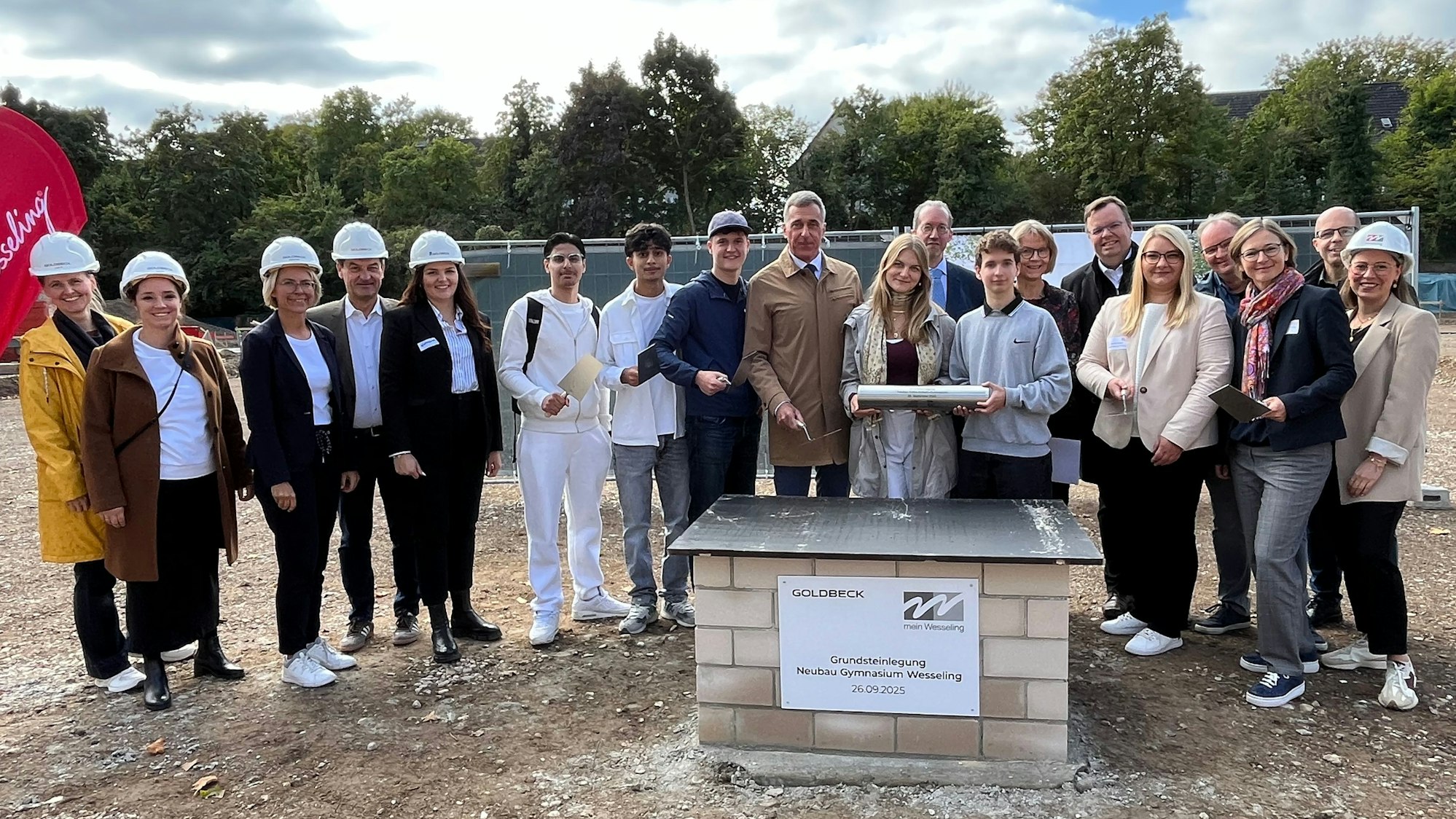 Das Foto zeigt Menschen bei einer Grundsteinlegung.