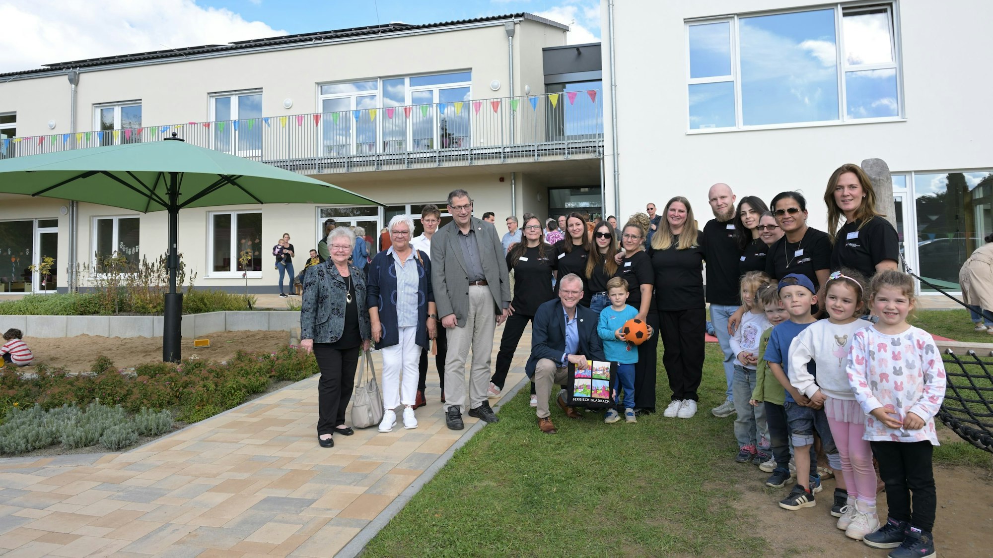 Erzieherinnen und Erzieher, Kinder und Vertreter der Awo sowie der Stadt stehen vor dem Gebäude.