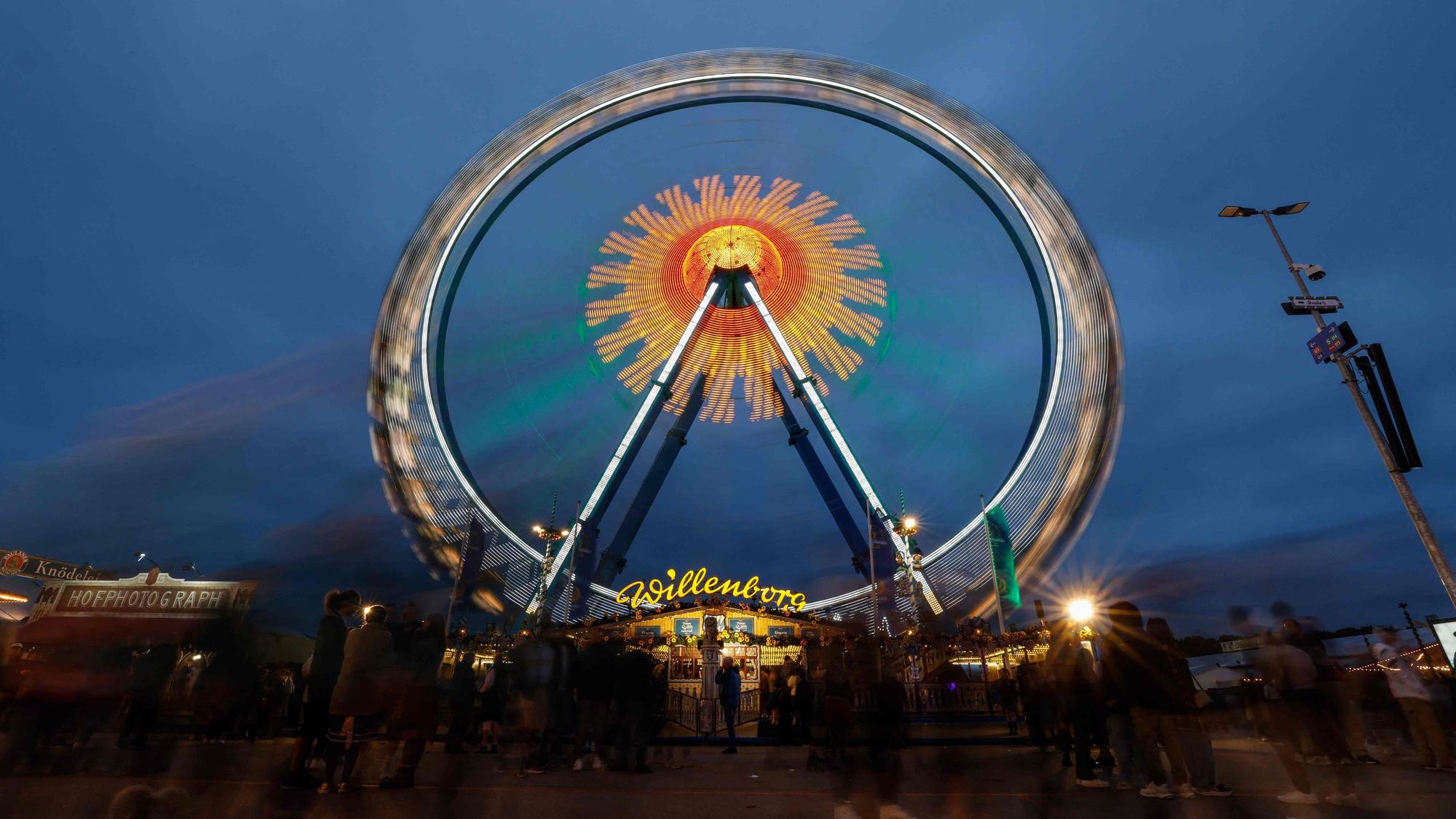 Die Lichter eines Riesenrads leichten während des 190. Oktoberfestes im Vergnügungspark auf der Theresienwiese in München (Symbolbild)