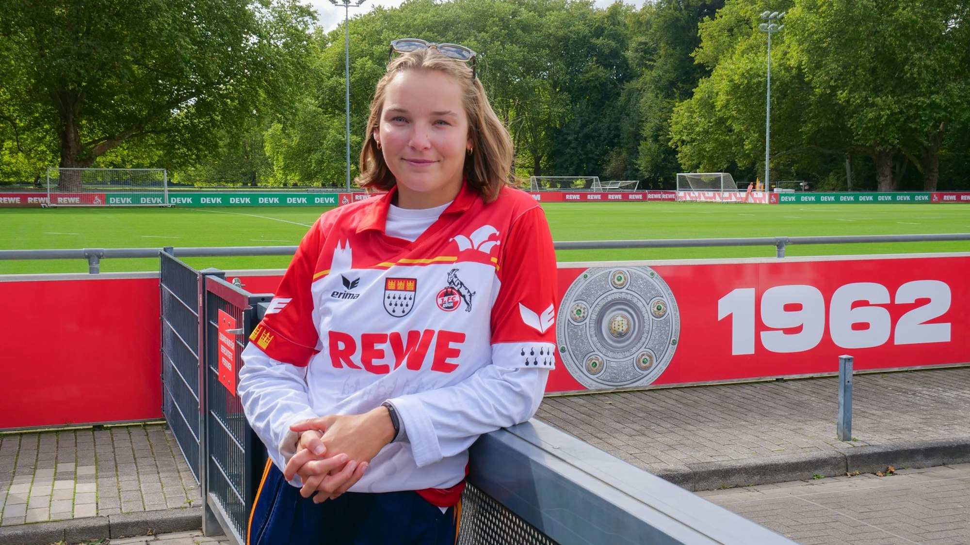 Auf dem Bild ist eine junge Frau im FC-Köln-Trikot auf einem Sportplatz zu sehen.