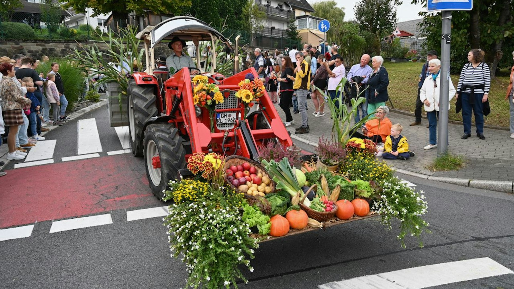 Ein geschmückter Traktor fährt im eine Kurve beim Erntezug in Vilkerath 2023.