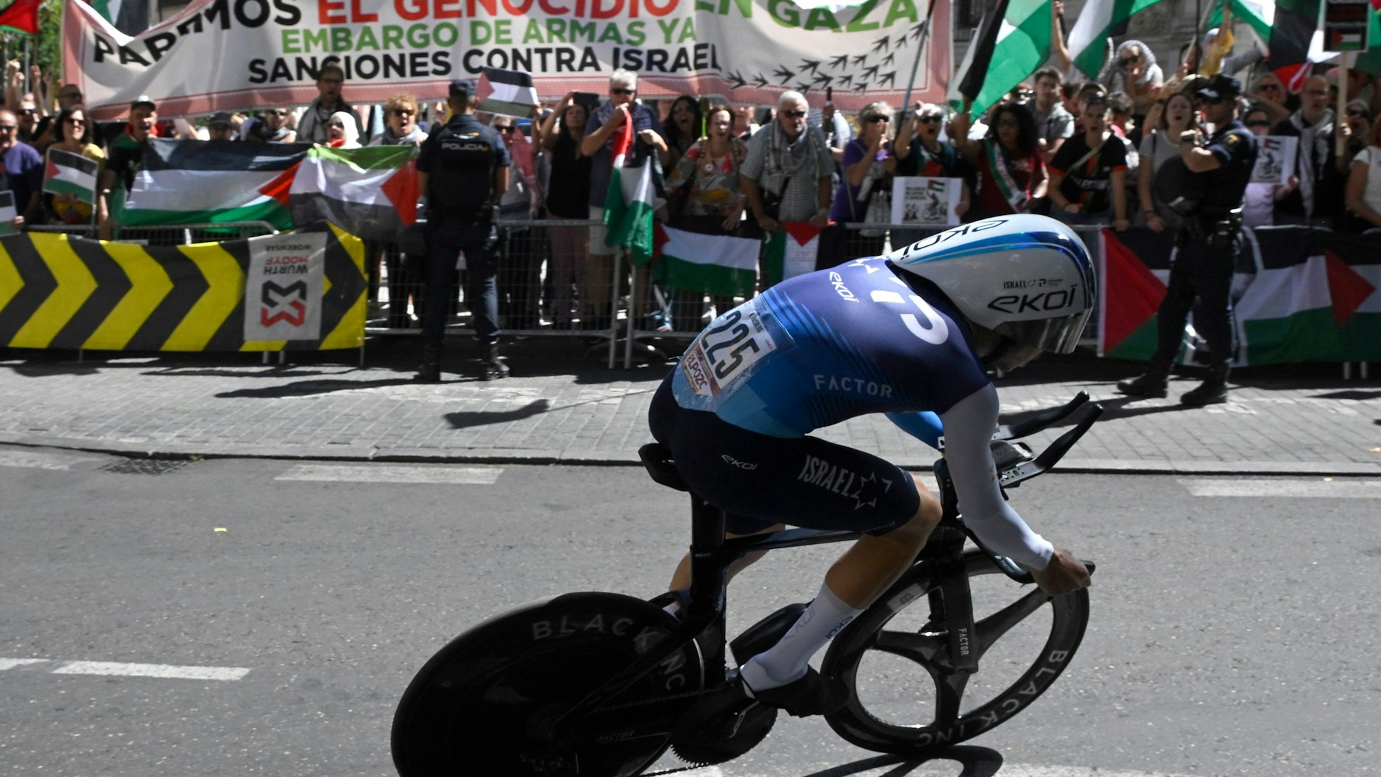 Nadav Raisberg vom Team Israel Premier Tech fährt bei der spanischen Vuelta an pro-palästinensischen Demonstranten vorbei.