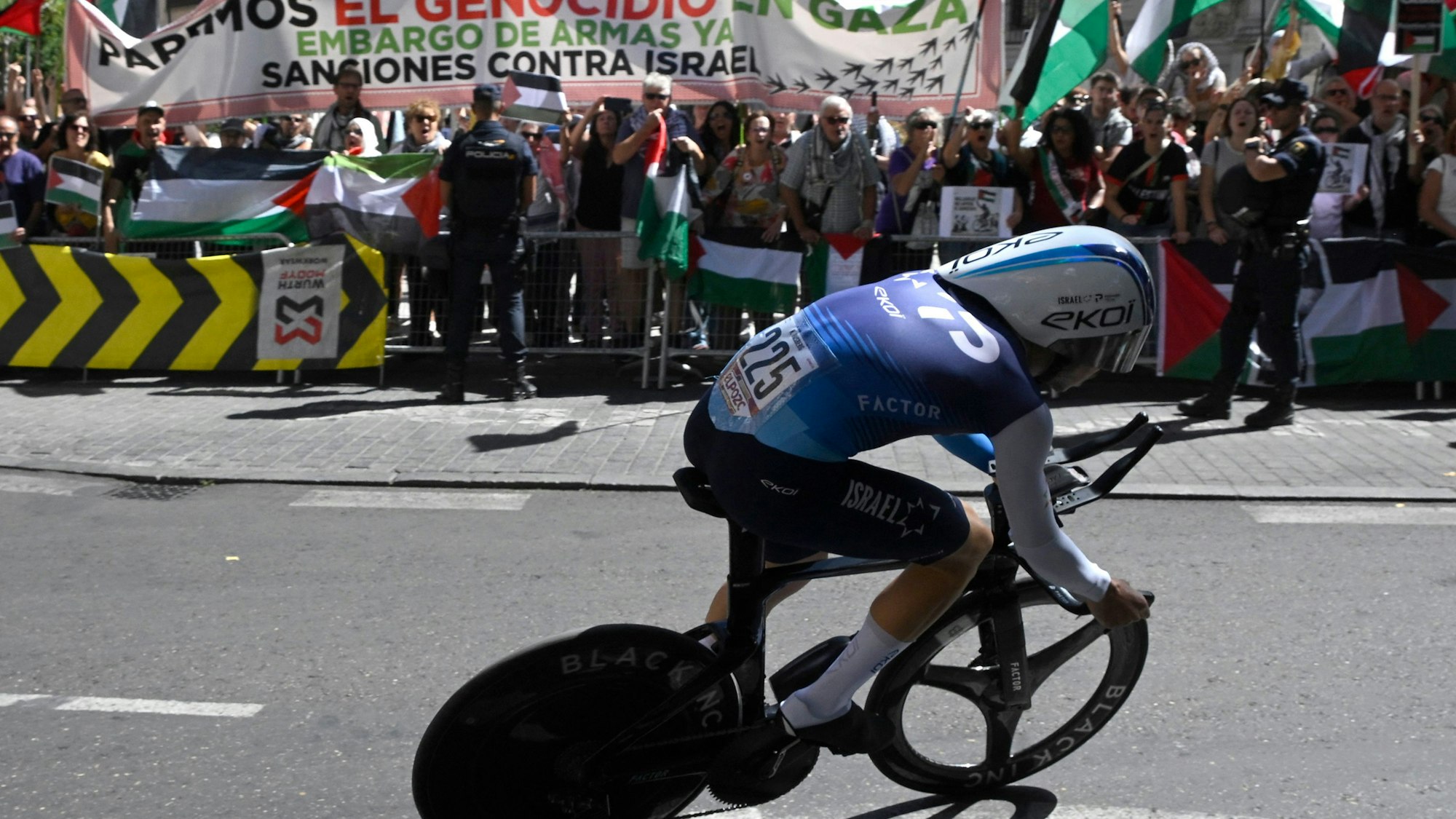 Nadav Raisberg vom Team Israel Premier Tech fährt bei der spanischen Vuelta an pro-palästinensischen Demonstranten vorbei.