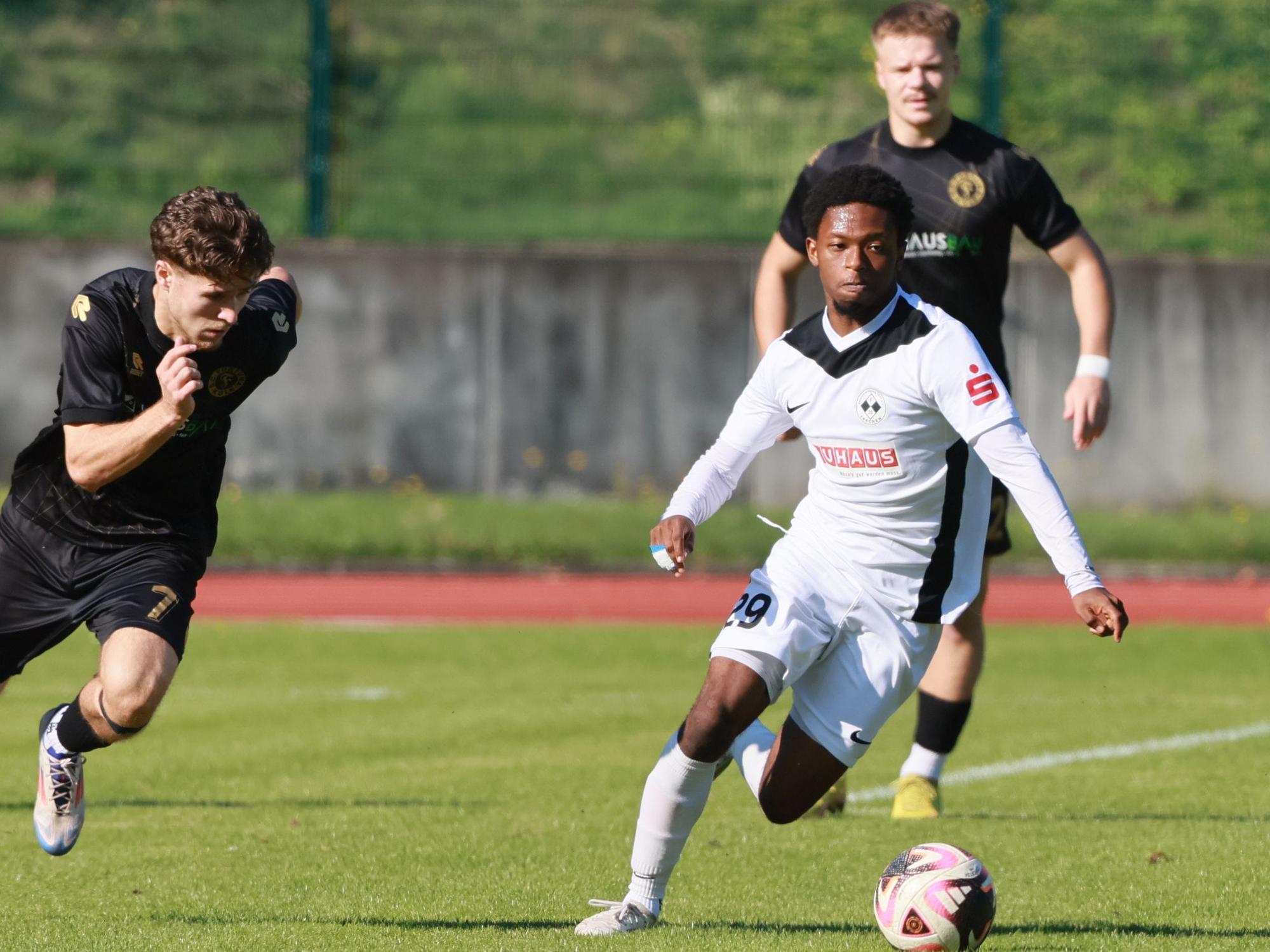 Das Bild zeigt einen Fußballer im hellen Trikot, der seinem dunkel gekleideten Kölner Gegenspieler enteilt.