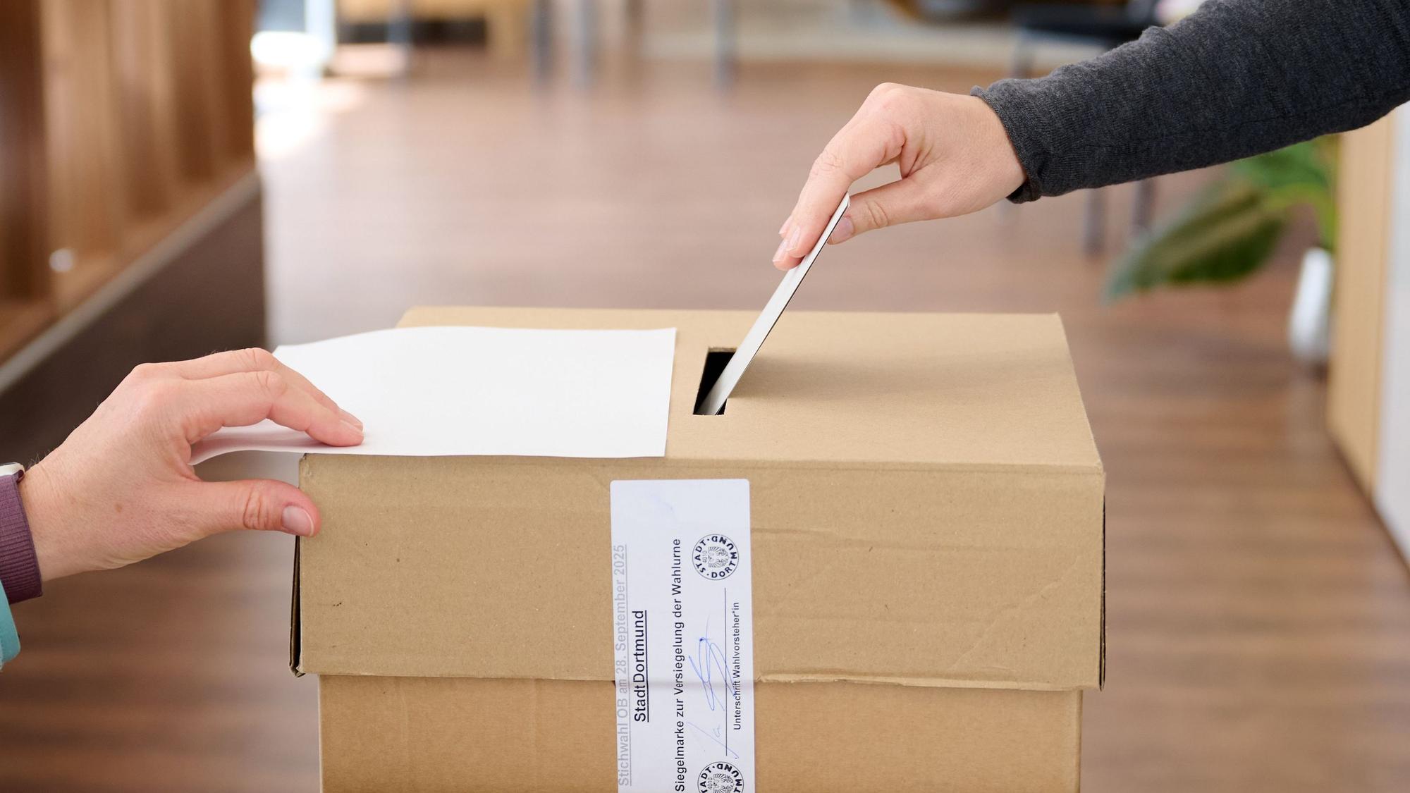 Ein Wahlumschlag wird in die einem Wahlraum in einem Bettengeschäft in die Urne gesteckt. (Symbolbild)
