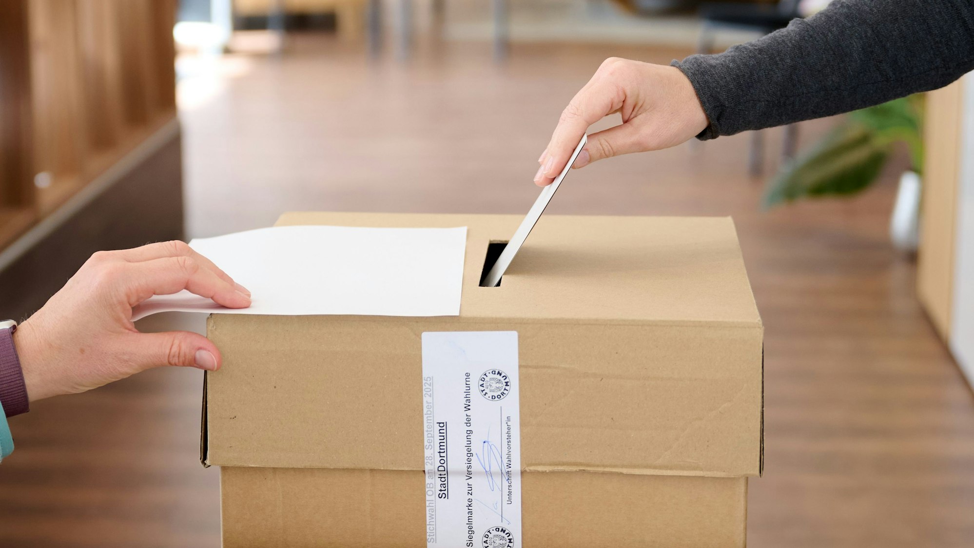 Ein Wahlumschlag wird in die einem Wahlraum in einem Bettengeschäft in die Urne gesteckt. (Symbolbild)